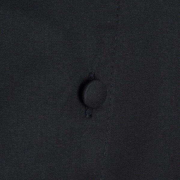A close up of the back of a black Chef Revival chef coat with buttons.