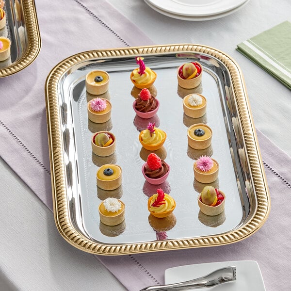 A rectangular metal catering tray with gold trim, displayed with assorted bite-sized desserts.