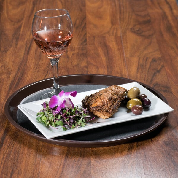 A brown plastic non-skid tray holding a plate of food and a glass of wine.