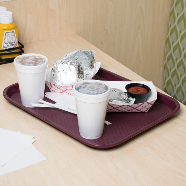 A customizable burgundy plastic fast food tray with food on it on a table.