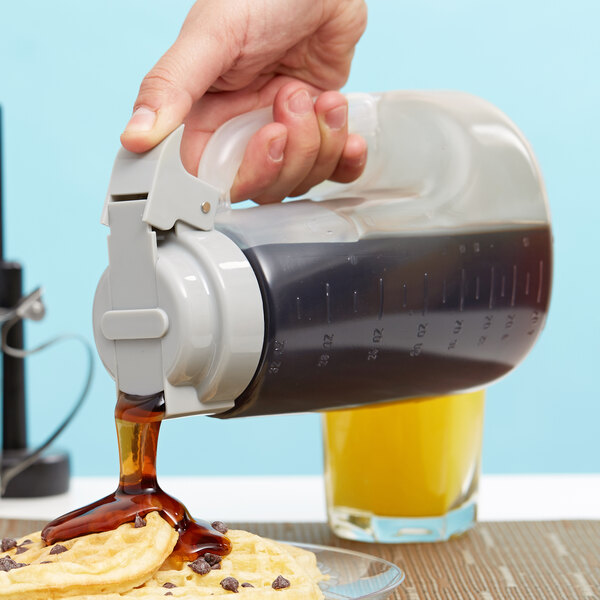 A person using a Tablecraft dispenser to pour syrup onto a waffle.