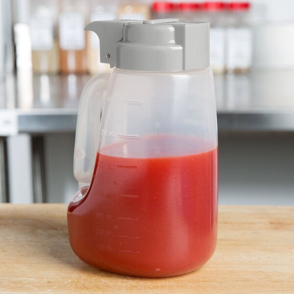 A Tablecraft 32 oz. dispenser jar with a gray lid on a counter.