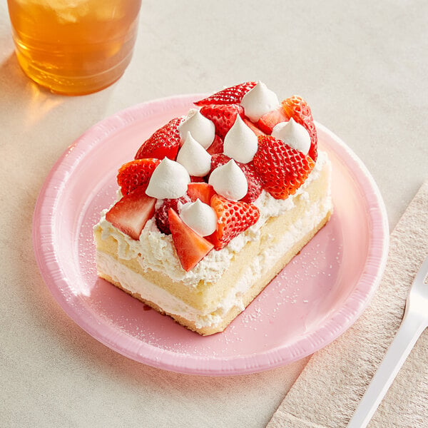 A piece of cake with strawberries and whipped cream on a Classic Pink plastic plate.