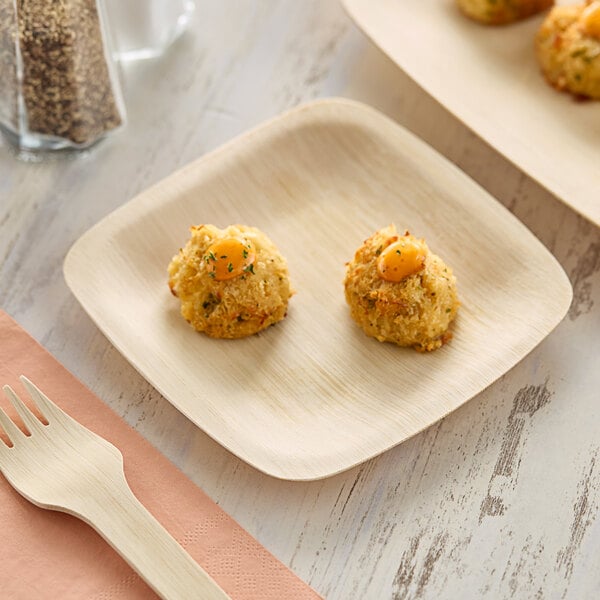 A Bambu Veneerware square appetizer plate with food on a table.