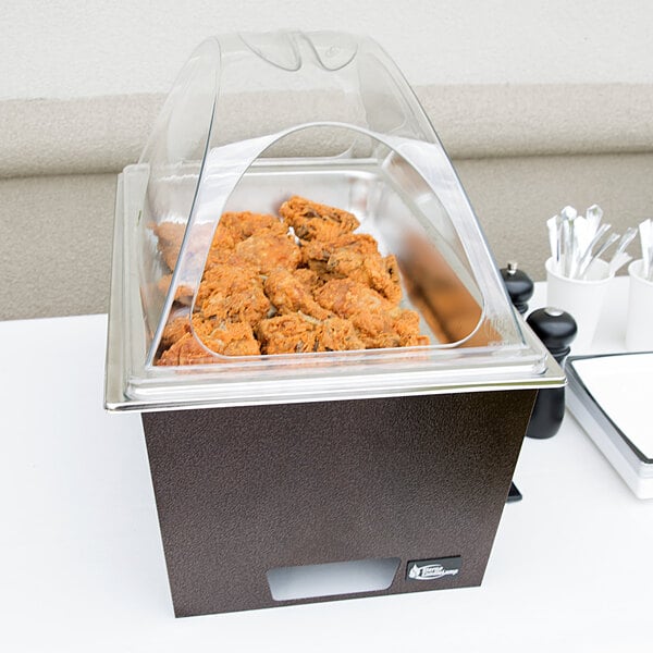 A Sterno copper vein chafing dish with food in it on an outdoor table.