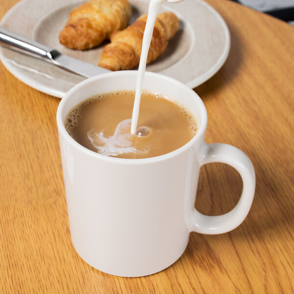 A white GET Tritan mug filled with coffee and milk on a table with croissants.