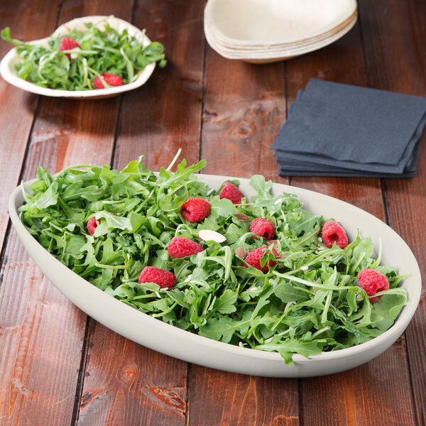 An ivory melamine bowl filled with salad greens, raspberries, and almonds.