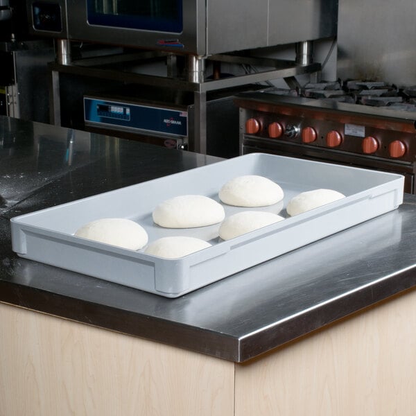 A MFG Tray gray fiberglass dough proofing box on a counter with dough in it.