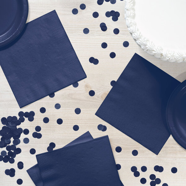 A navy blue 1/4 fold luncheon napkin on a table with navy blue plates.