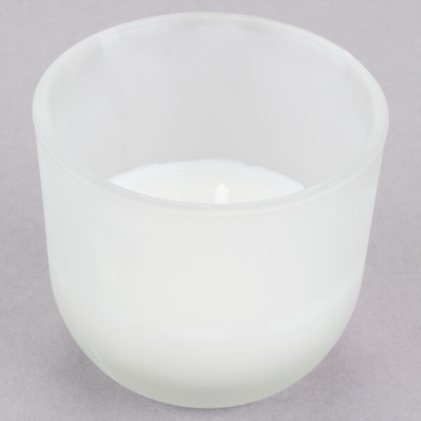 A white wax candle in a glass cup.