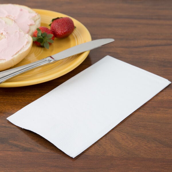 A plate with food and a white Creative Converting 3-ply guest towel on the table.