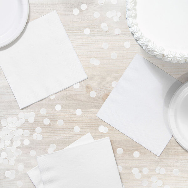 A table with white plates and a white Creative Converting luncheon napkin.