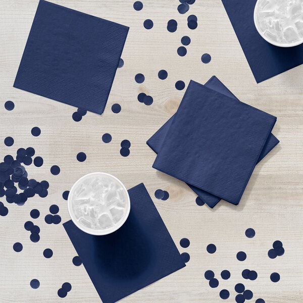 A white table with a blue napkin with navy blue polka dots.