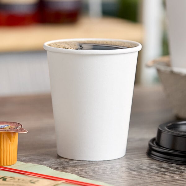 A white Choice paper hot cup with a drink in it on a table.