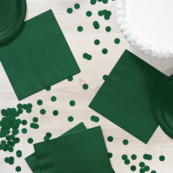 A table with a green Creative Converting luncheon napkin and confetti.