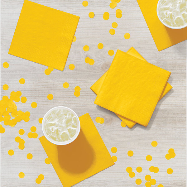 A table with yellow School Bus Yellow luncheon napkins and cups of liquid.