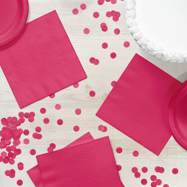 A table set with hot magenta pink napkins and confetti.