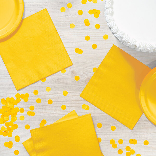 A yellow Creative Converting luncheon napkin on a table with yellow and white decorations.
