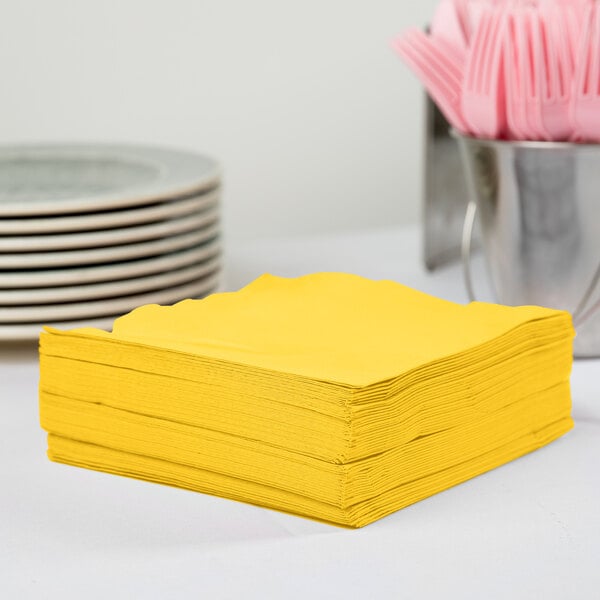 A stack of Creative Converting School Bus Yellow luncheon napkins.