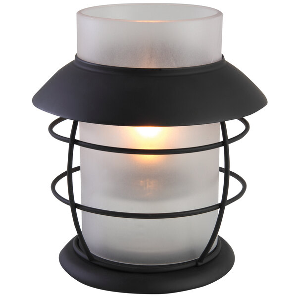 A white Sterno Hyannis frost lamp with a lit candle inside.