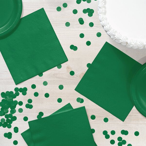 A table with emerald green napkins and confetti.