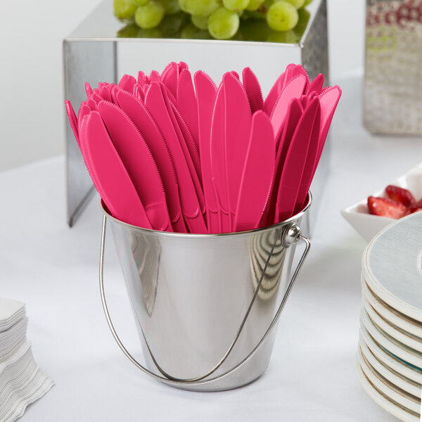 A bucket filled with hot magenta pink Creative Converting plastic knives.