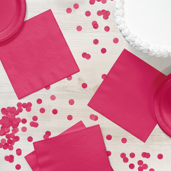 A table with a pink napkin and confetti.