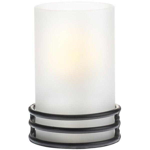 A white candle holder with black wire around it on a black stand.