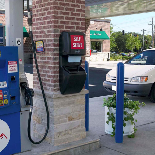 A black Commercial Zone Vue-T-Ful Isle windshield washing service center with a red sign and paper towel dispenser next to a gas pump.