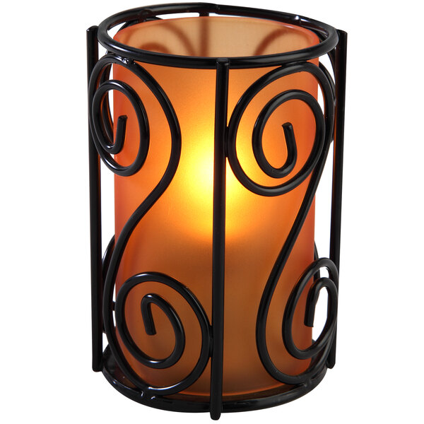 An orange frosted glass candle holder with a lit candle inside.