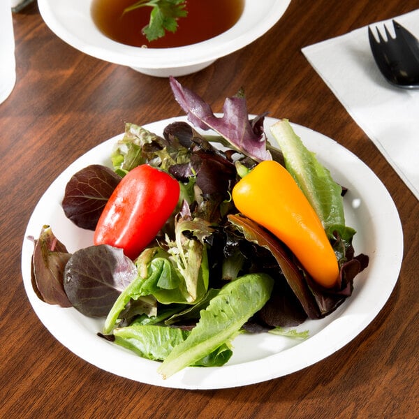 A white paper plate with salad on it at a salad bar.