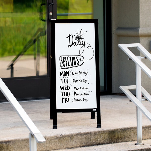 An Aarco black aluminum A-frame sign with white porcelain marker board on the steps of a building.