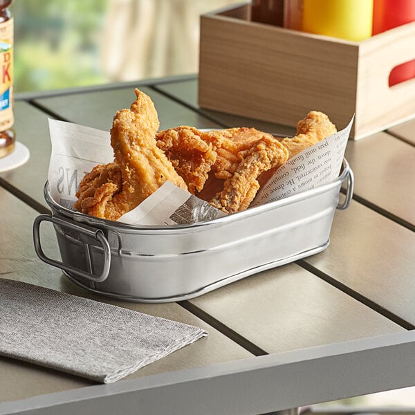 An American Metalcraft stainless steel metal tub filled with fried chicken on a table.