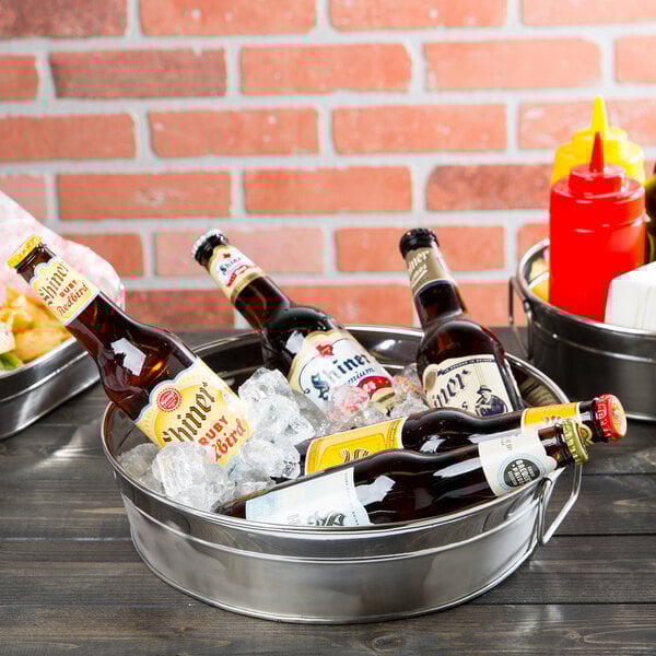 An American Metalcraft stainless steel round metal tub filled with beer bottles and ice.