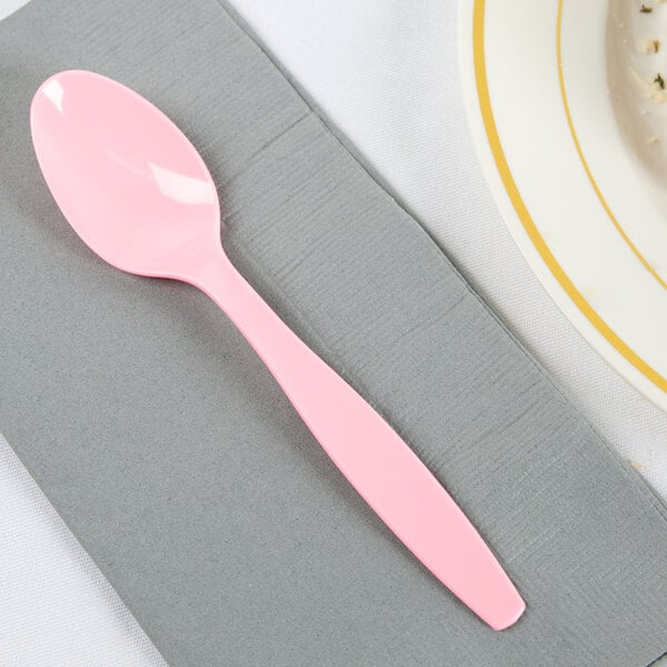 A Creative Converting Classic Pink plastic spoon on a napkin.