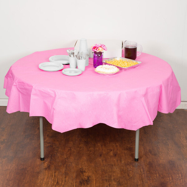 A table with a Creative Converting candy pink OctyRound table cover, plates, and cups with food on it.