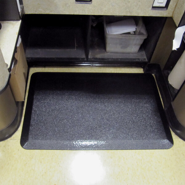 A Walrus Hide black anti-fatigue floor mat on a grey kitchen floor.