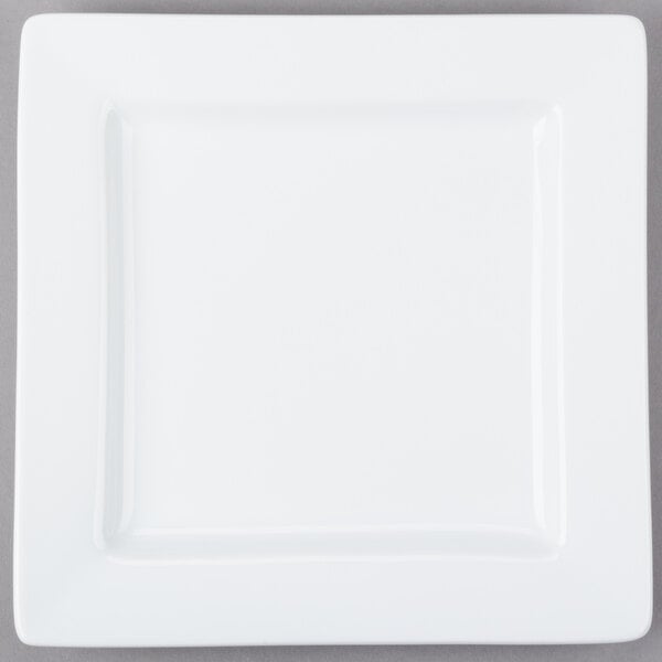 A Libbey ultra bright white porcelain square plate with a white rim on a gray surface with a fork.