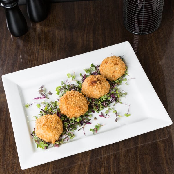 A Libbey rectangular white porcelain plate with three small balls of food on it.