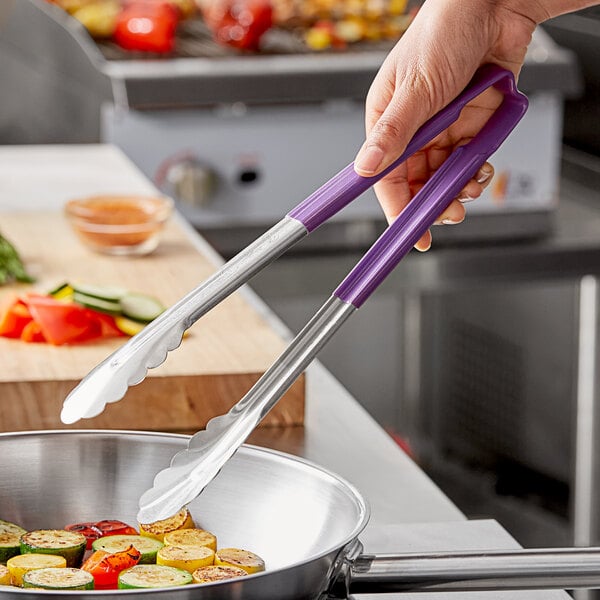 A person holding a pair of Vollrath Jacob's Pride stainless steel tongs with a purple Kool-Touch handle over food.