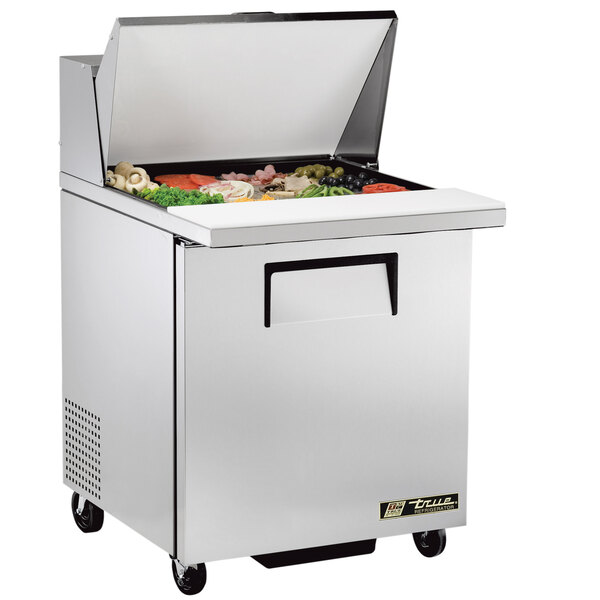 A large silver True commercial refrigerator with food inside.