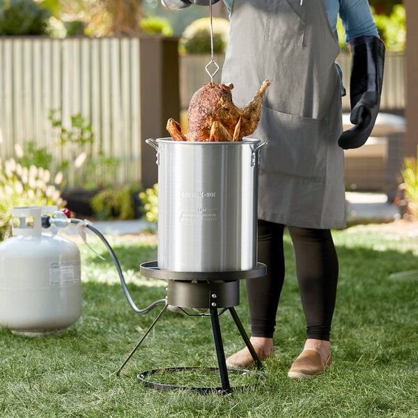 A woman cooking a turkey in a Backyard Pro turkey fryer kit.