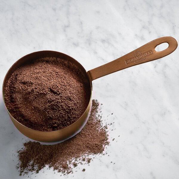 A copper pot with a bowl of Ghirardelli Chocolate Frappe Mix powder.