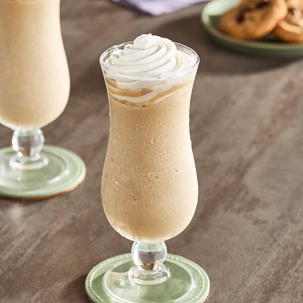 A glass of white Ghirardelli White Mocha Frappe with whipped cream on top.