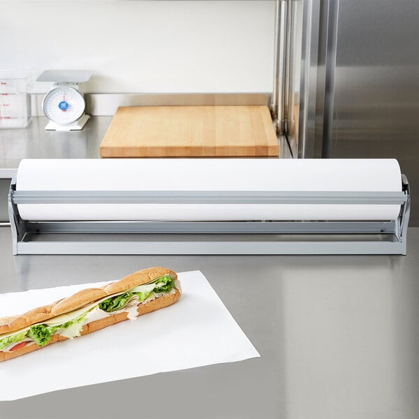 A sandwich wrapped in paper with lettuce and cheese on a cutting board.