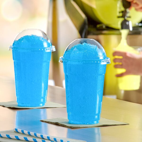 A plastic cup filled with bright blue raspberry slushy ice and topped with a clear dome lid.