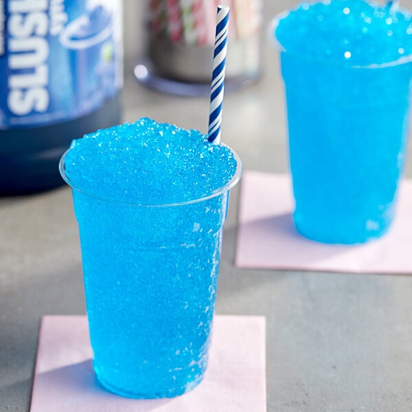 A blue plastic cup of Carnival King Blue Raspberry slushy with a blue and white striped straw.