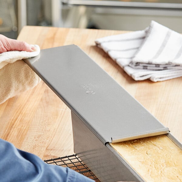 A person putting a loaf of bread into a Chicago Metallic aluminized steel pan.