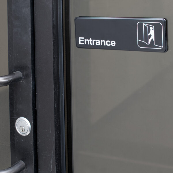 A black and white sign that says "Entrance" on a door.