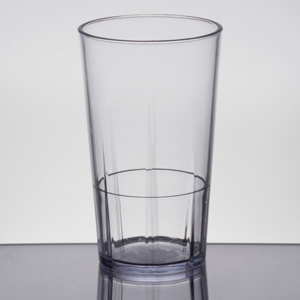 A clear Cambro plastic tumbler on a table with a red liquid inside.